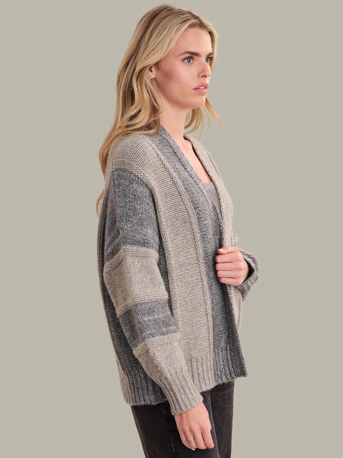 Woman wearing a gray and beige striped sweater against a plain background