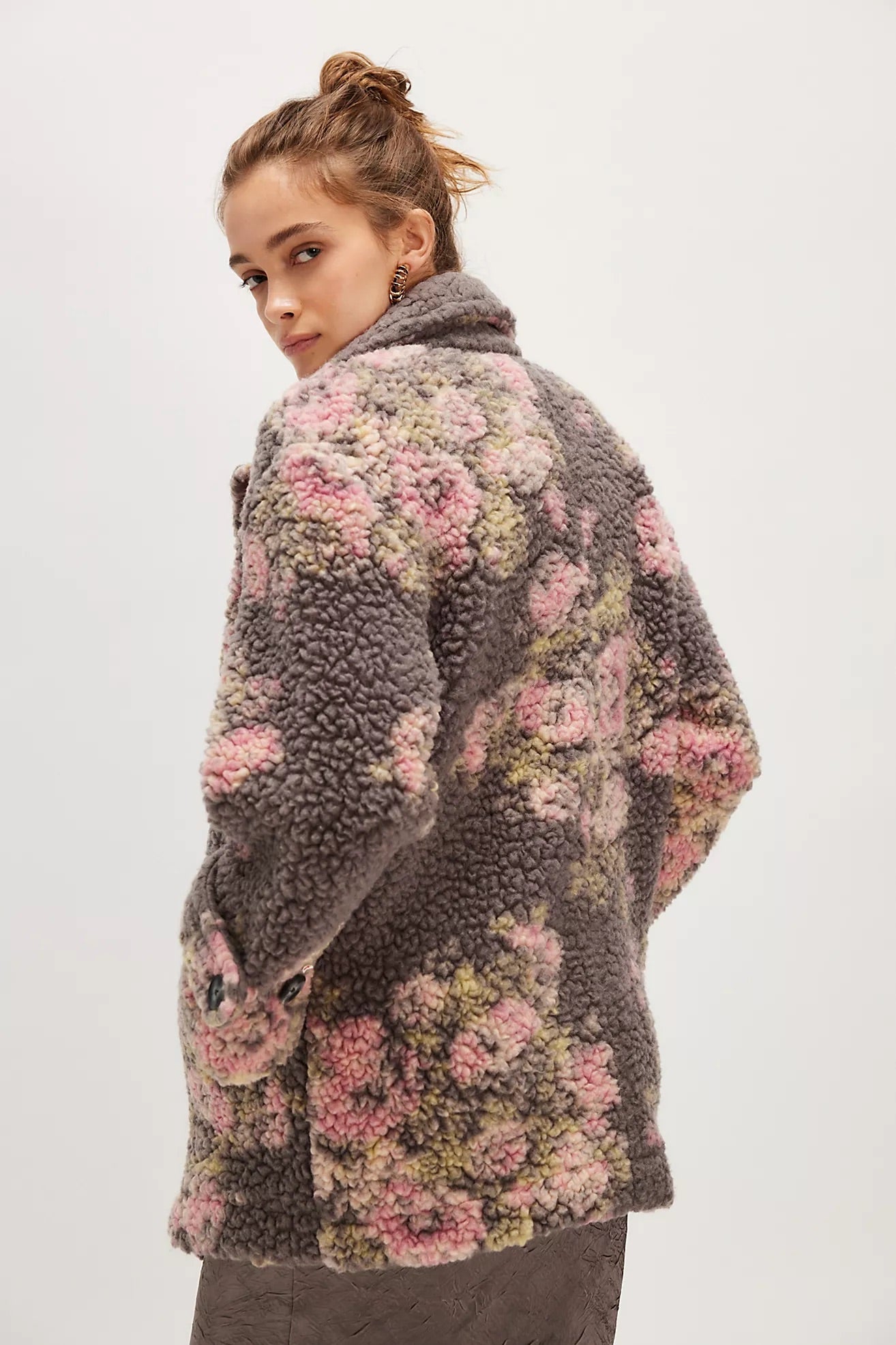 Woman wearing a floral-patterned coat on a plain background