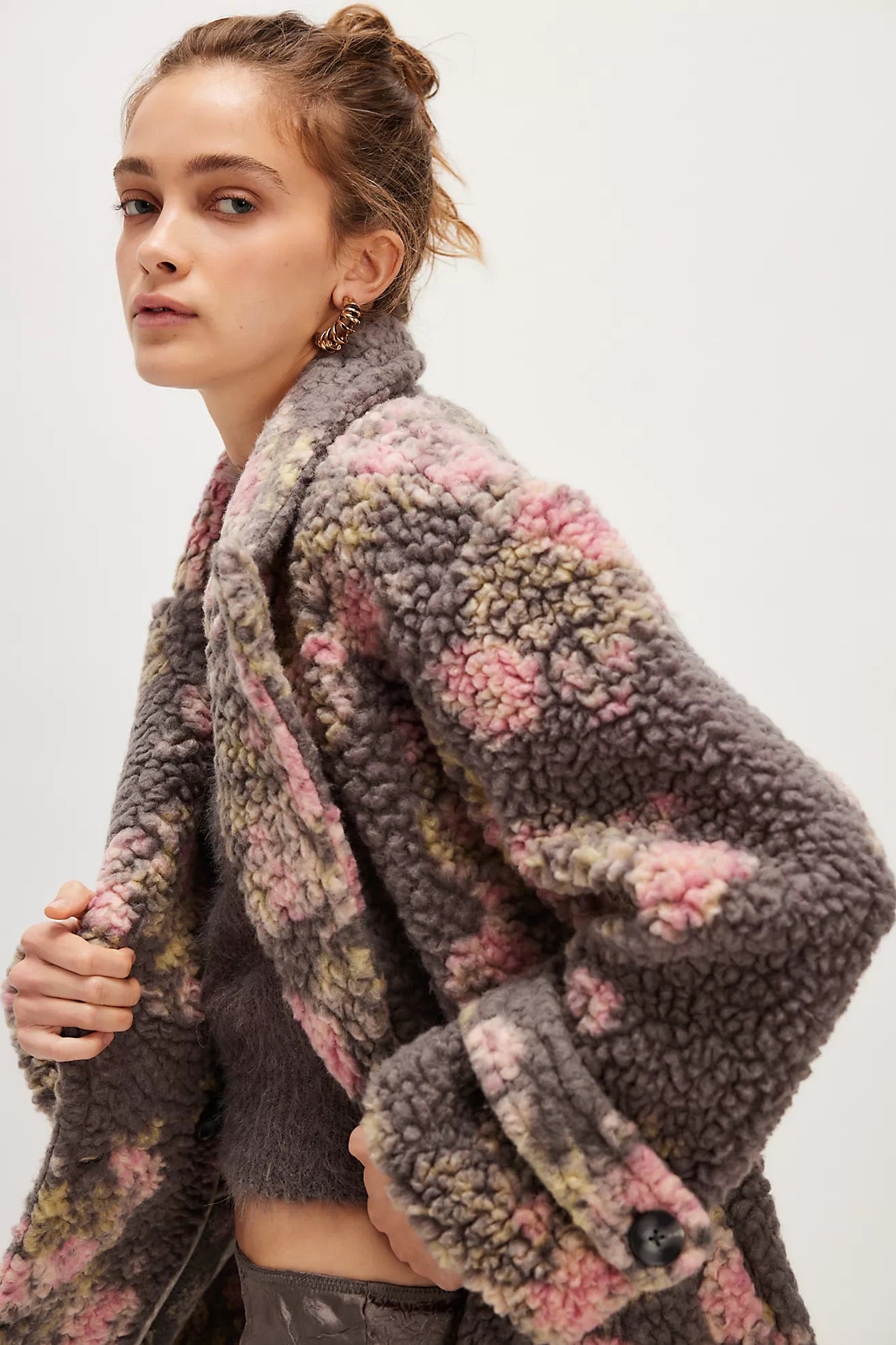 Woman wearing a textured, multicolored coat against a white background