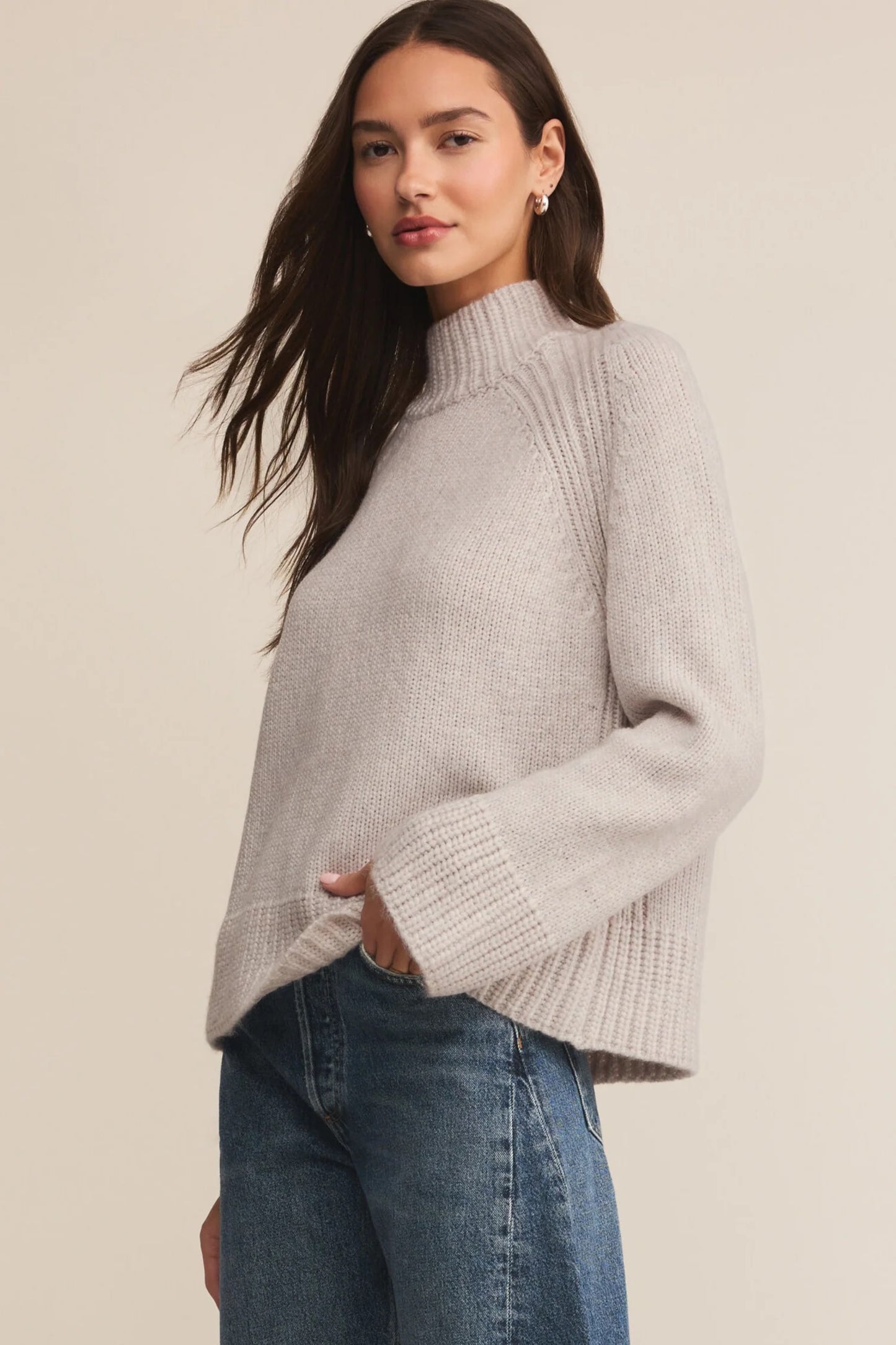 Woman wearing a light gray knit sweater against a neutral background