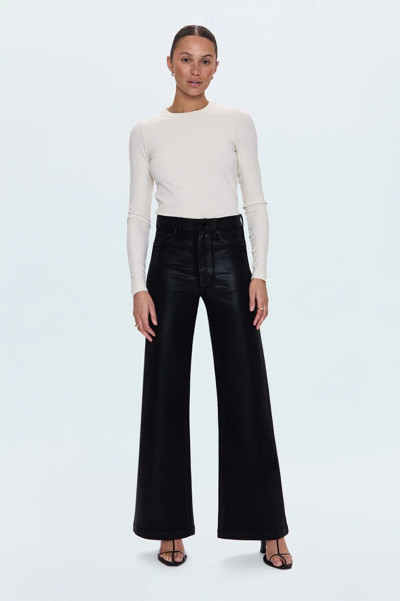 Woman wearing a white long-sleeve top and black high-waisted pants on a light gray background
