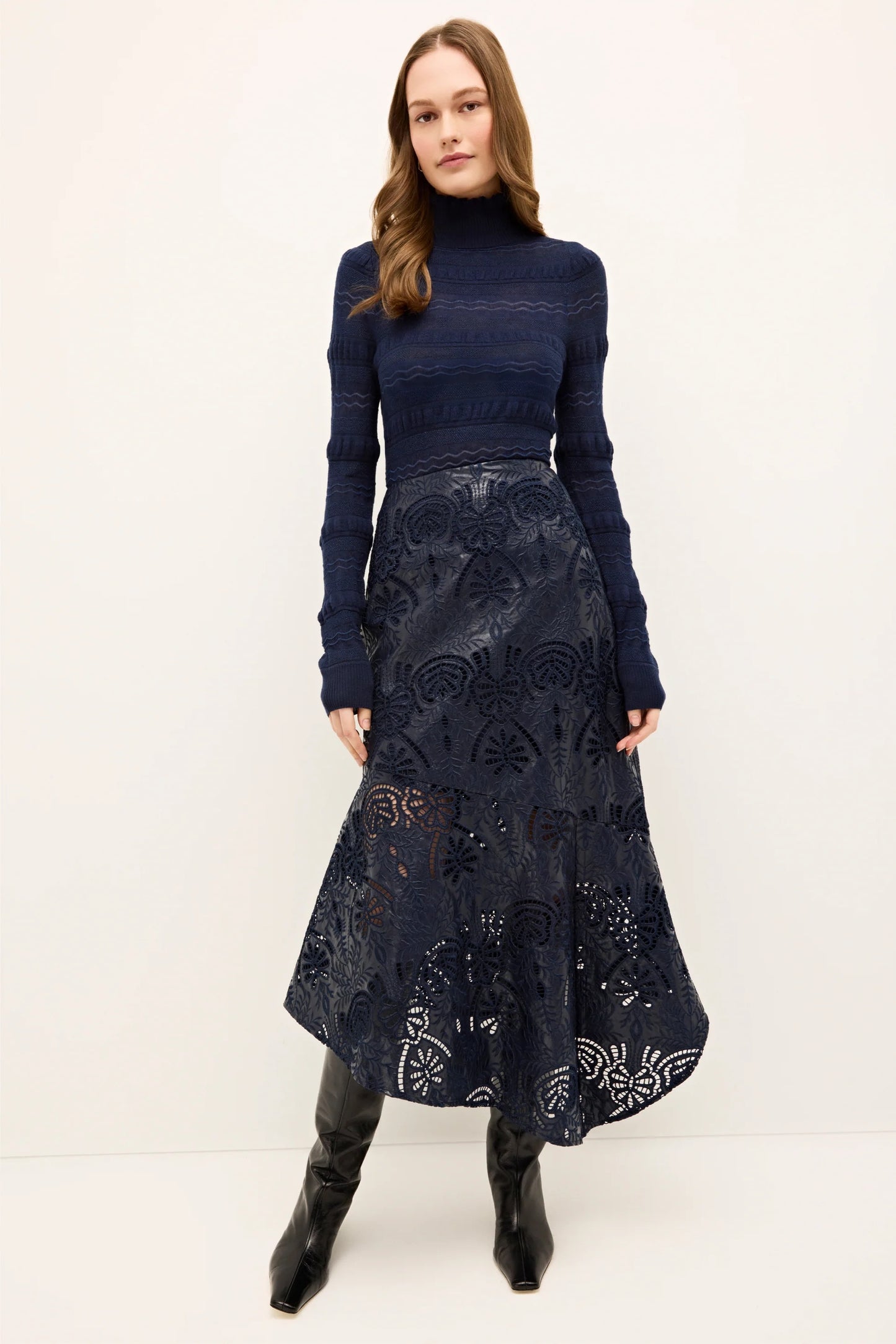 Woman wearing a navy blue top and patterned skirt on a white background