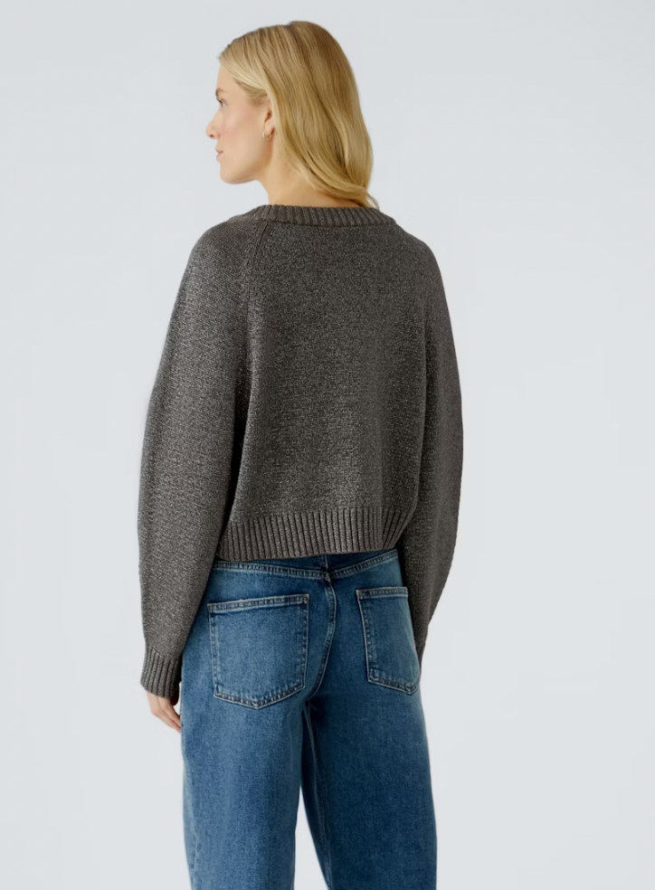 Person wearing a gray sweater and blue jeans on a light gray background
