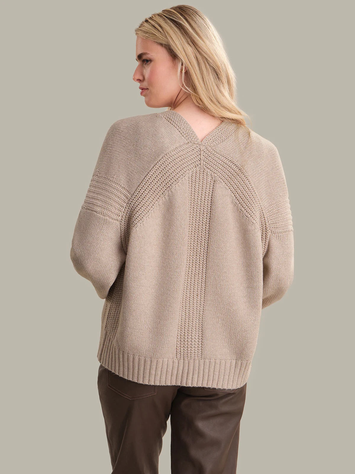 Woman wearing a beige sweater with a neutral background