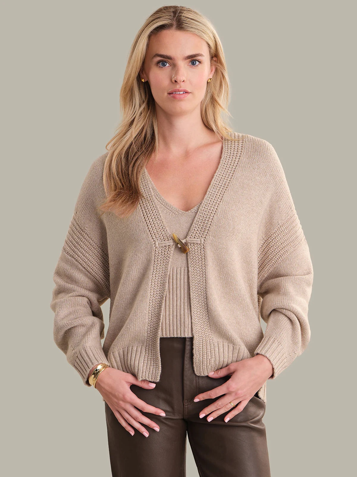 Woman wearing a beige cardigan against a plain background