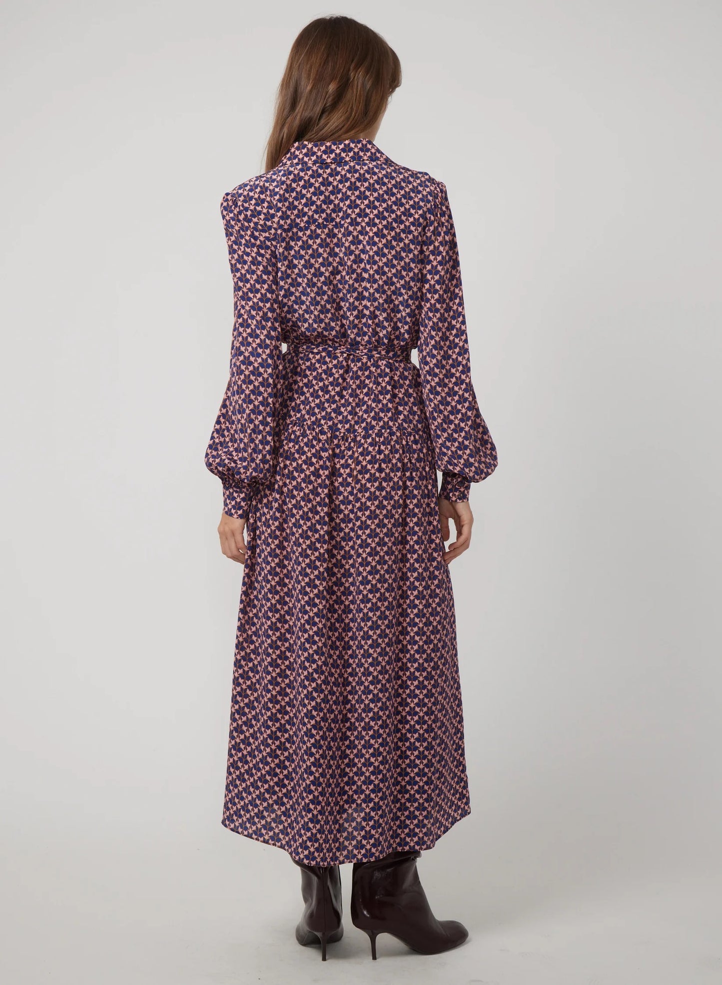 Woman wearing a long patterned dress on a white background