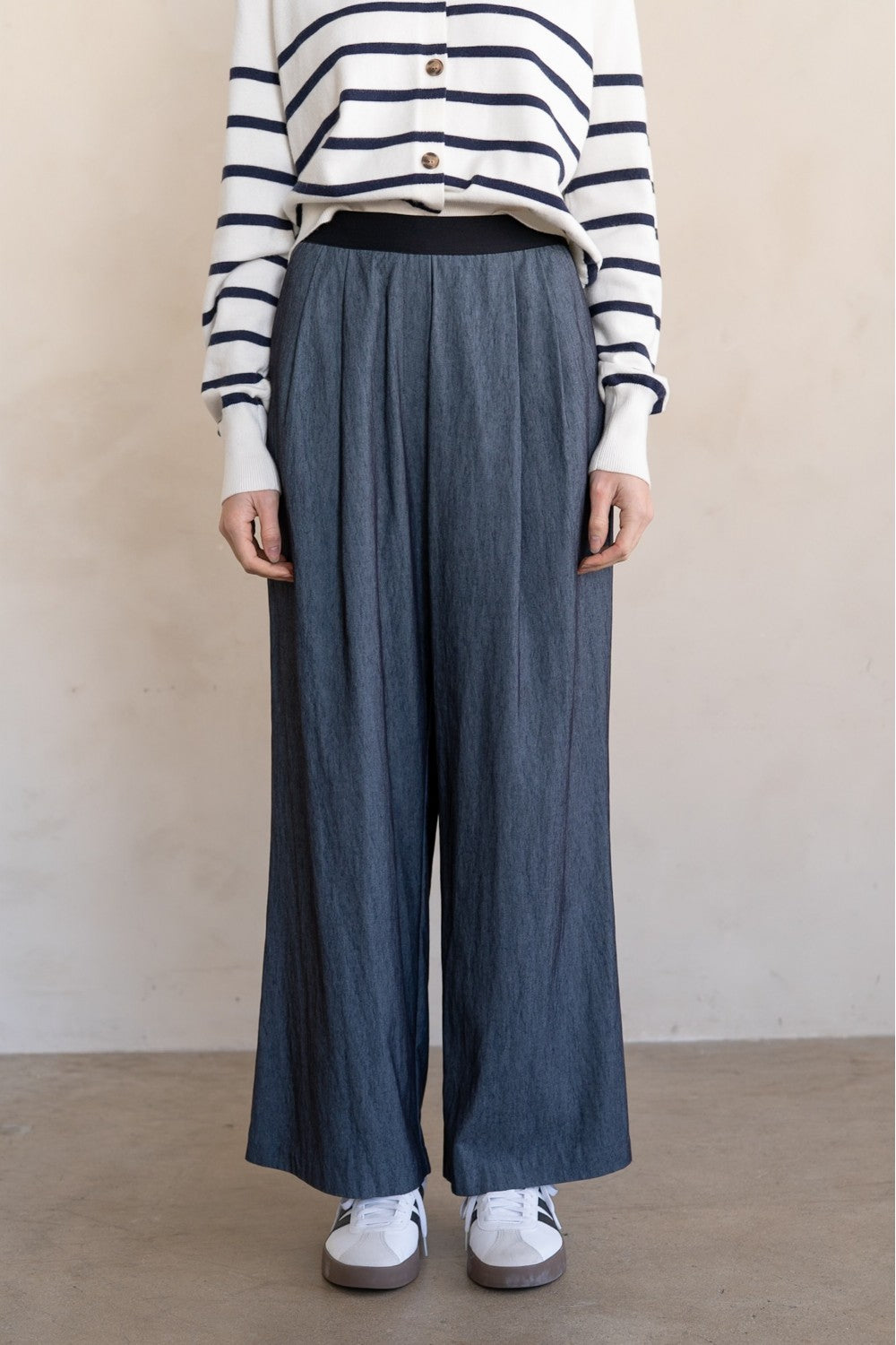 Person wearing a striped sweater and wide-leg jeans against a plain background