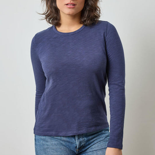 Person wearing a blue long-sleeve shirt against a plain background