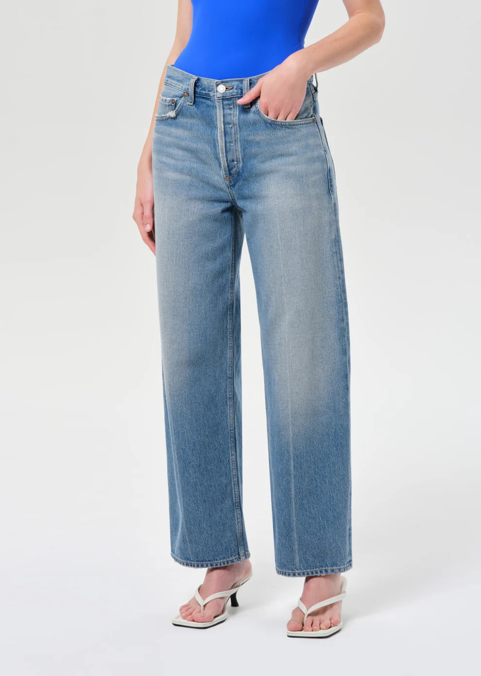 Person wearing blue jeans and a blue top on a white background