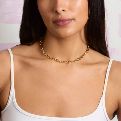 Woman wearing a gold chain necklace with a blurred abstract background