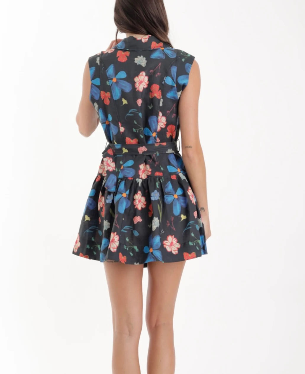 Woman wearing a sleeveless dress with a colorful floral pattern on a white background