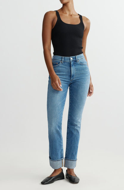 Person wearing blue jeans and a black tank top on a white background