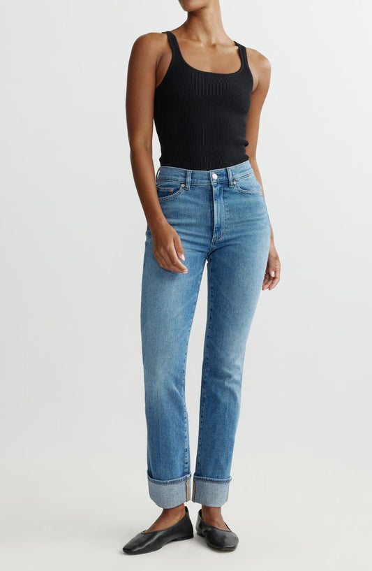 Person wearing blue jeans and a black tank top on a white background