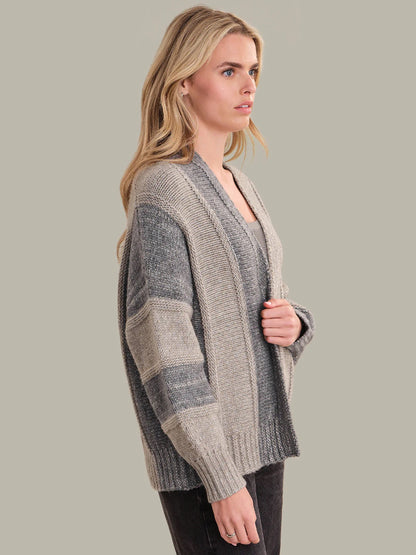 Woman wearing a gray and beige striped sweater against a plain background