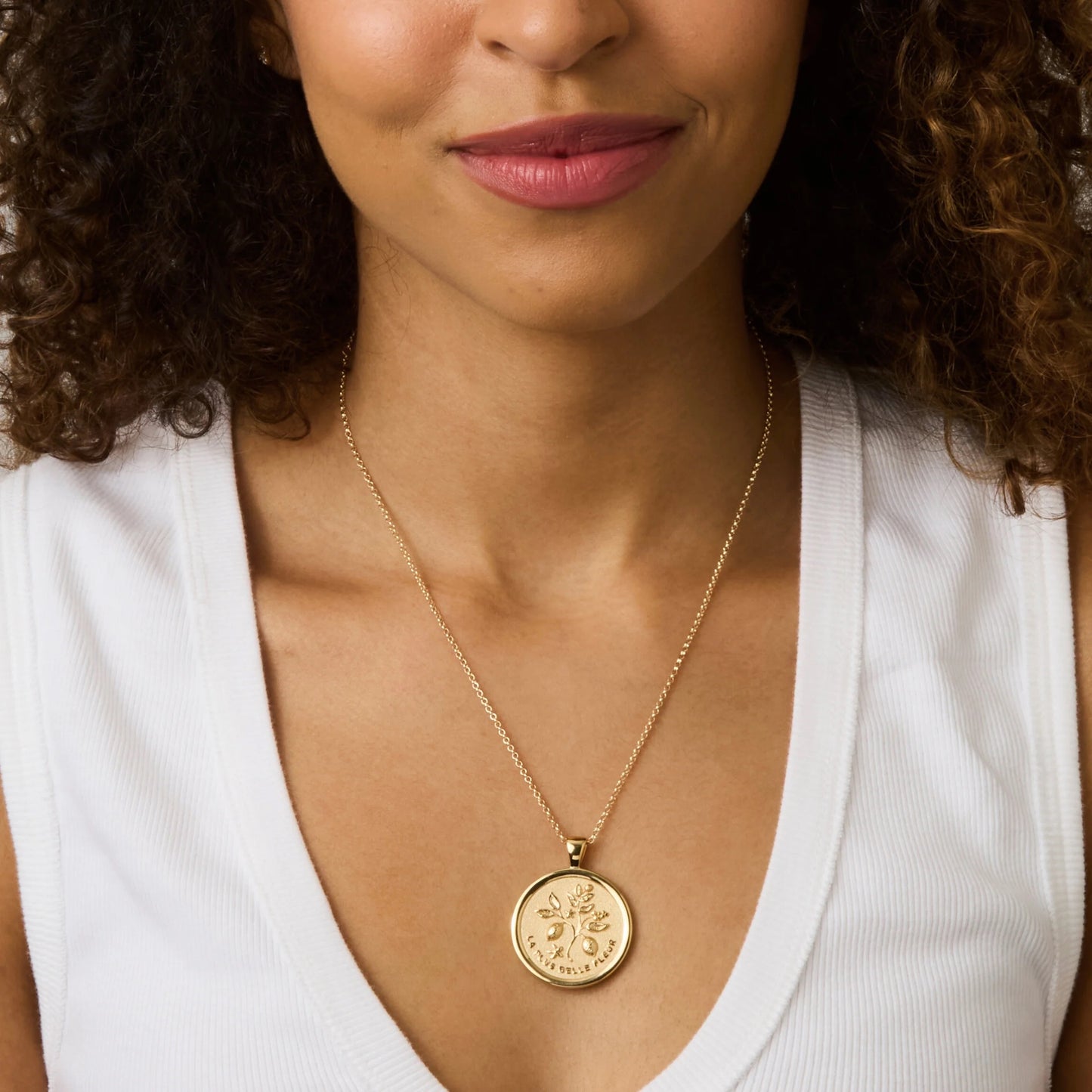 Woman wearing a gold necklace with a pendant