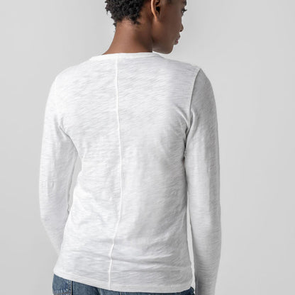 Person wearing a white long-sleeve shirt against a gray background