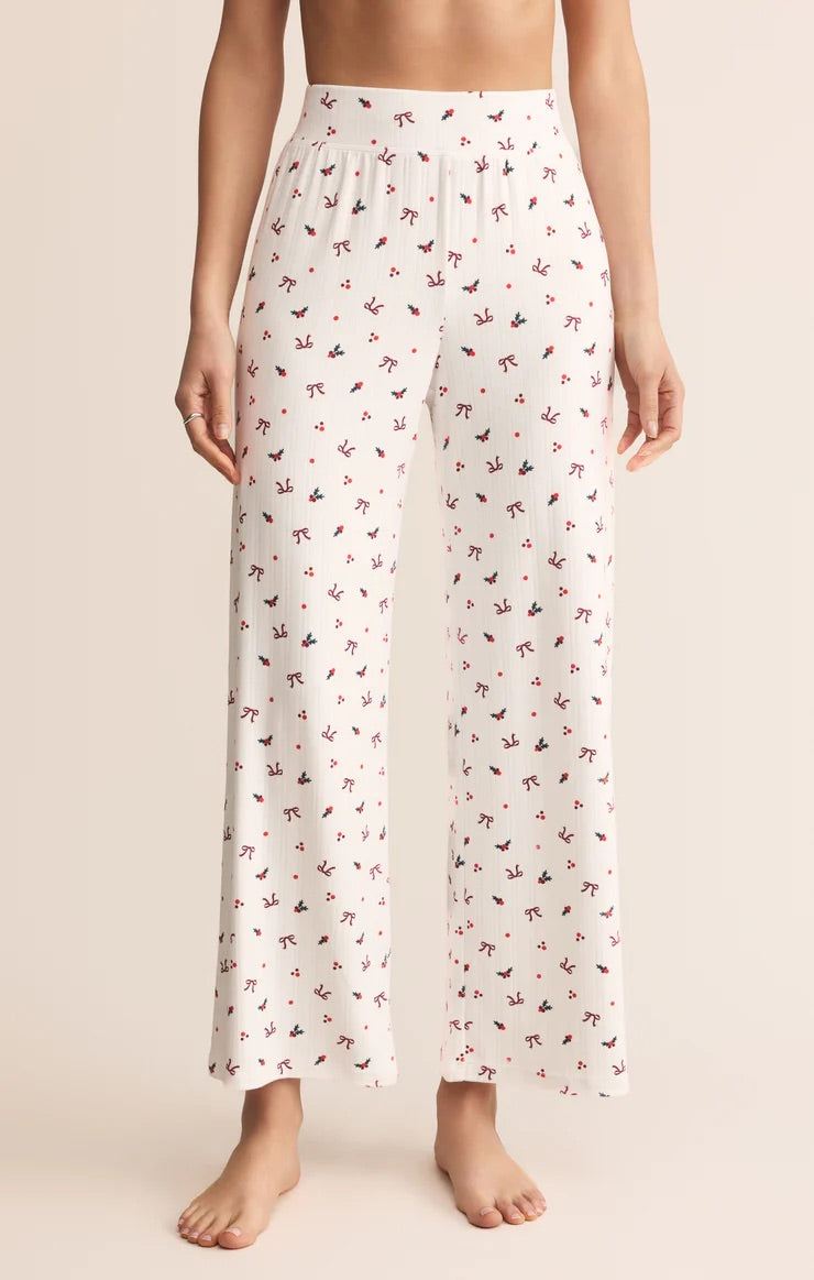 White pajama pants with a subtle pattern worn by a person on a beige background