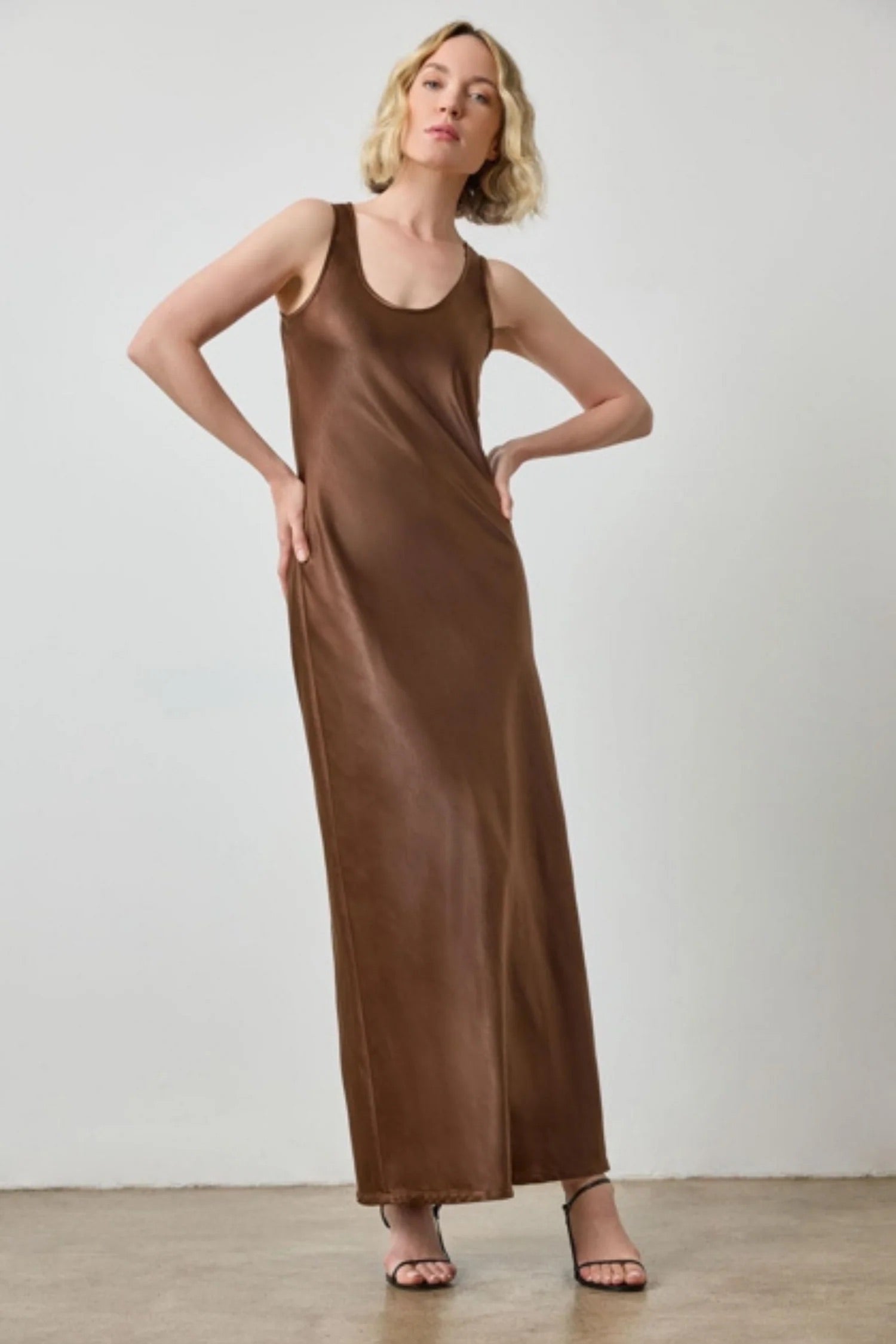 Woman wearing a brown slip dress against a plain background