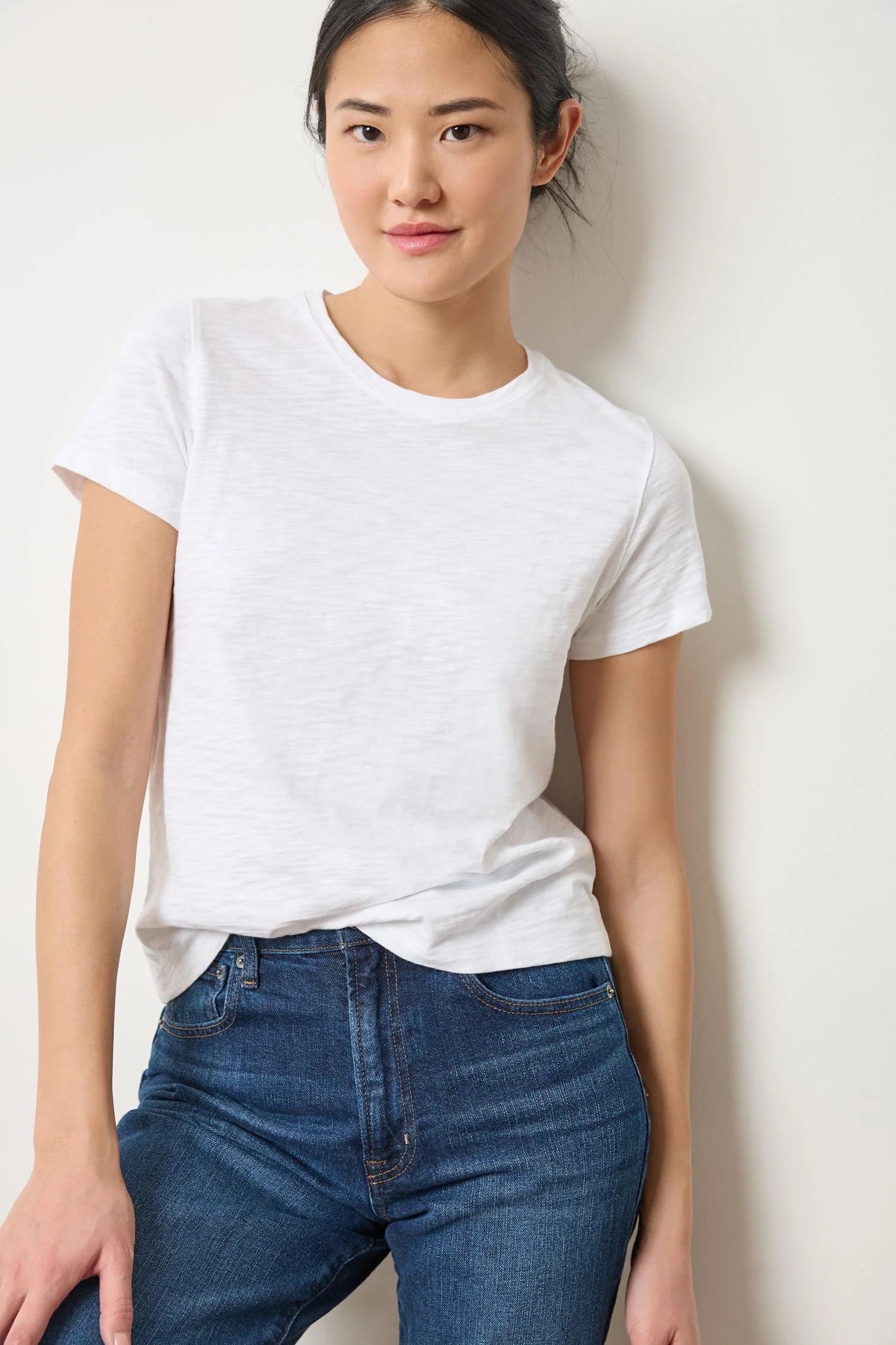 Person wearing a white t-shirt and blue jeans against a plain background
