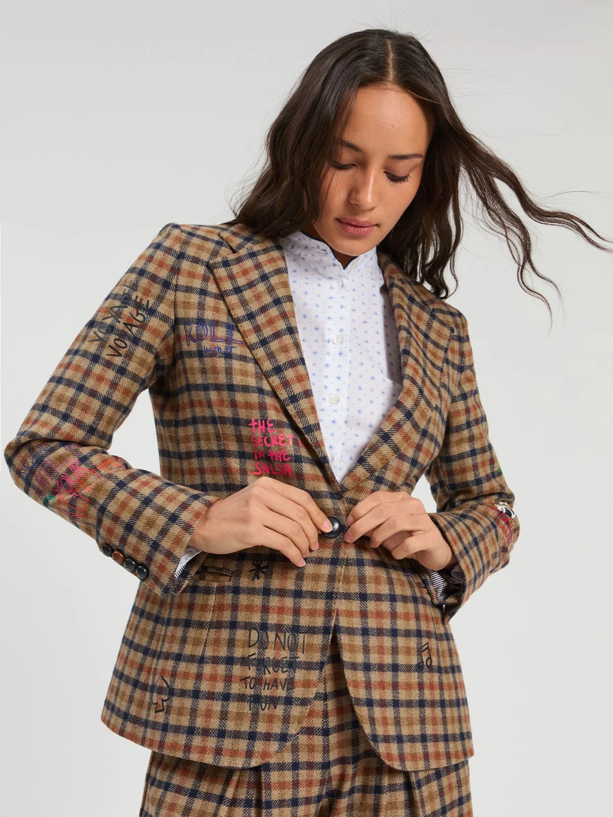 Woman wearing a plaid suit with a white shirt underneath on a plain background