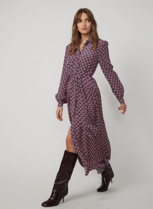 Woman wearing a patterned dress with a slit and black boots on a white background