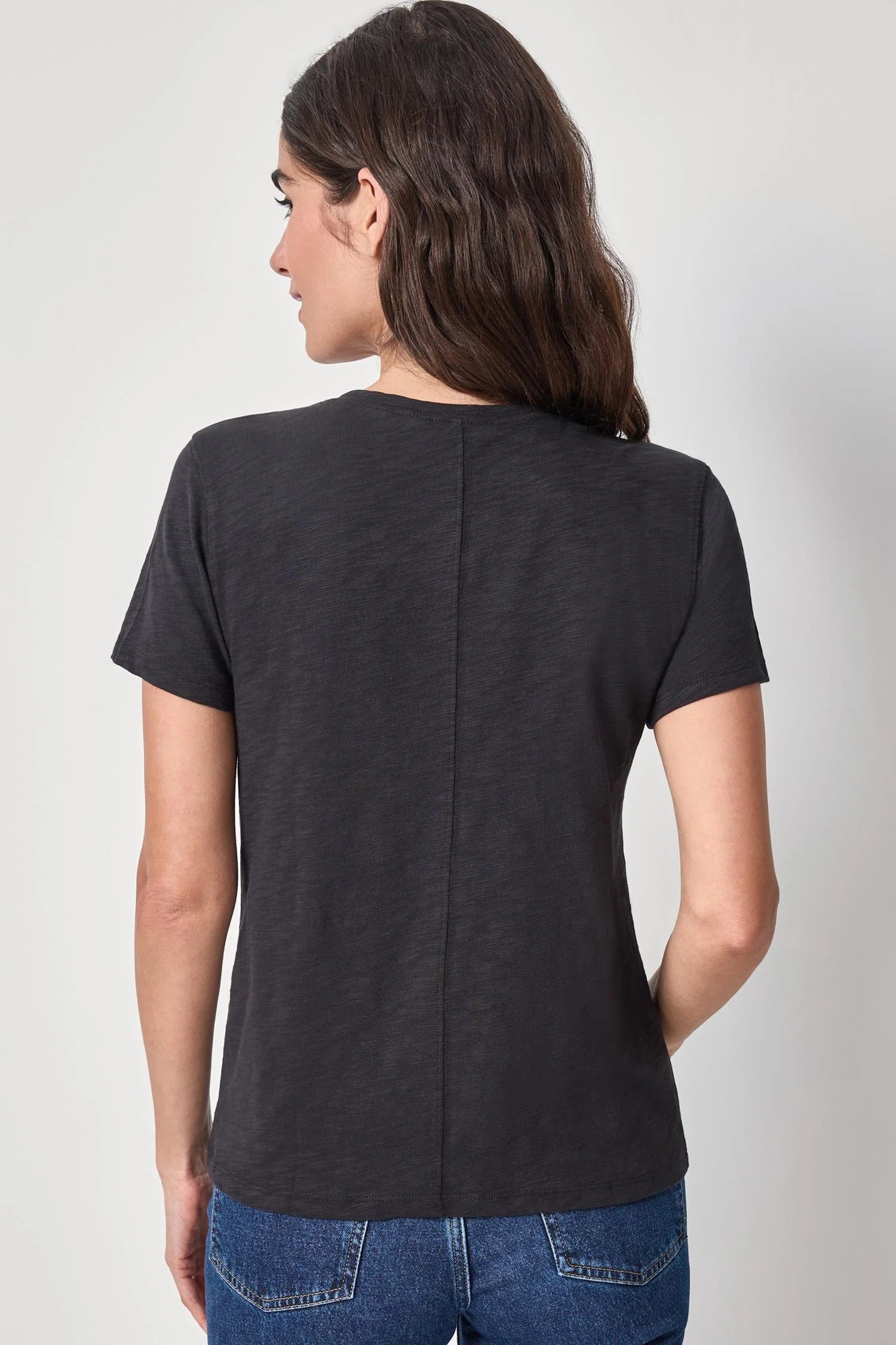 Person wearing a black t-shirt and blue jeans on a white background