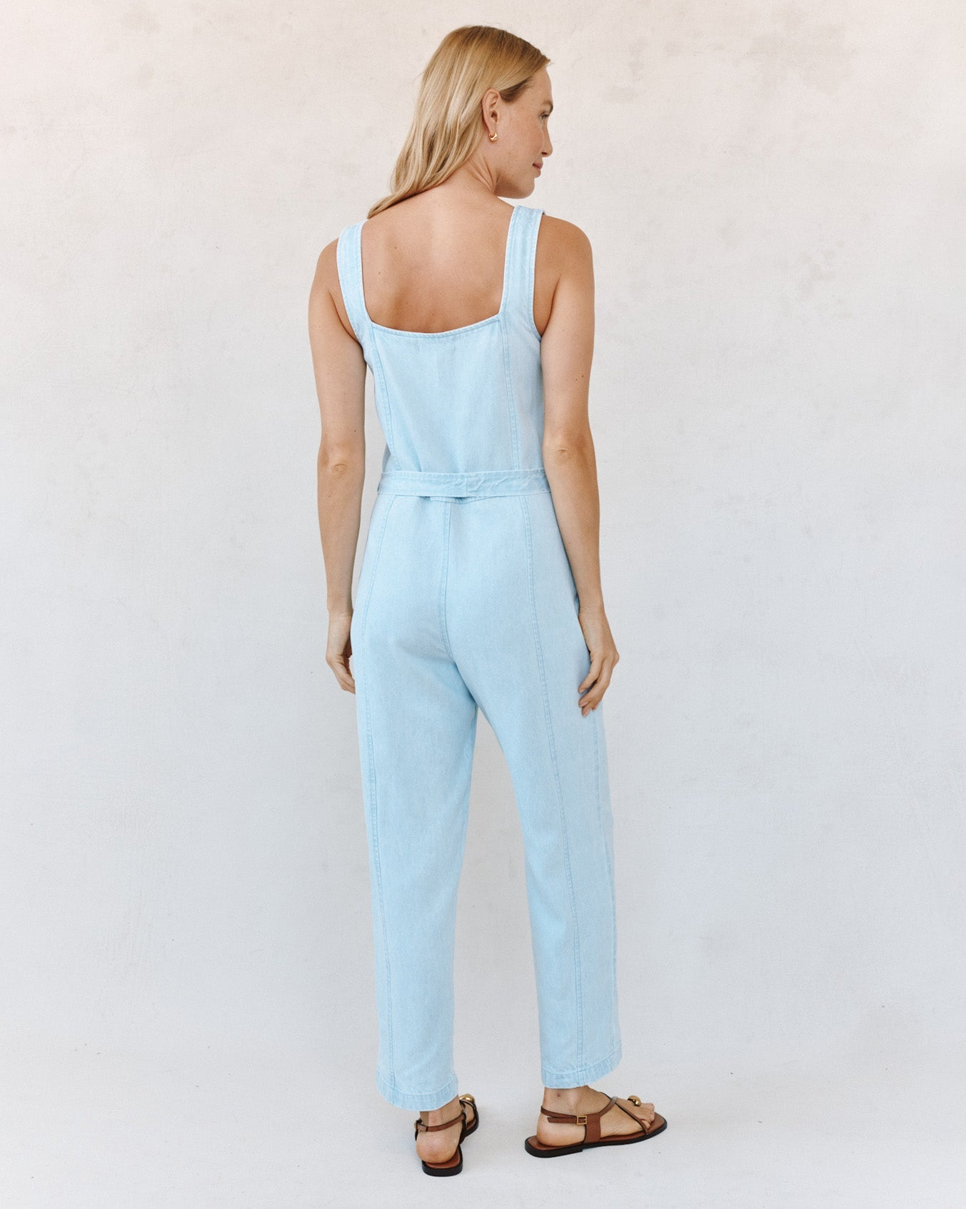Woman wearing a light blue jumpsuit against a white background