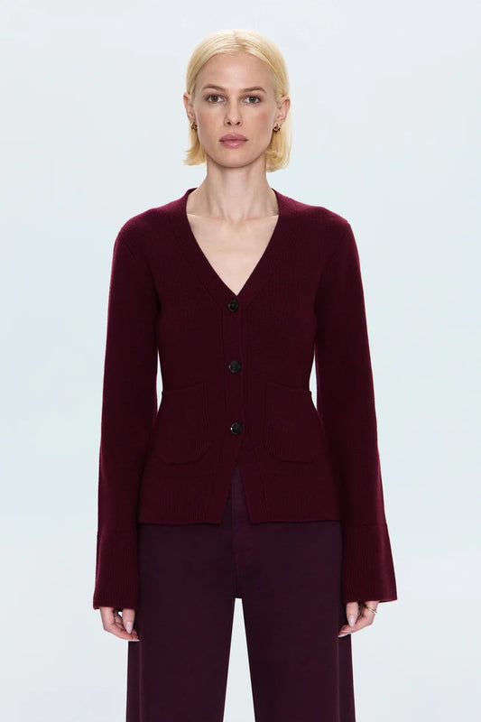 Woman wearing a burgundy cardigan and pants on a light gray background.