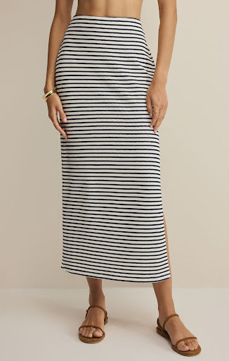 Person wearing a black and white striped skirt on a beige background