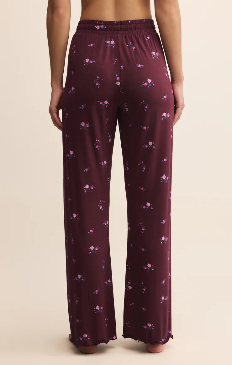Maroon pajama pants with floral pattern worn by a person on a beige background