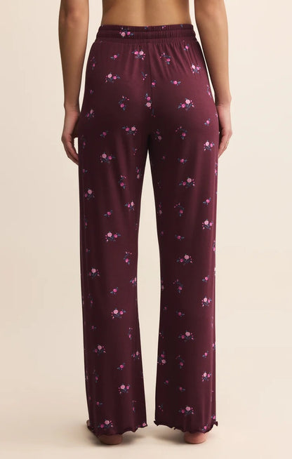 Maroon pajama pants with floral pattern worn by a person on a beige background