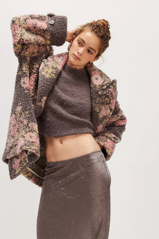 Woman wearing a floral jacket over a gray sweater and pants on a white background