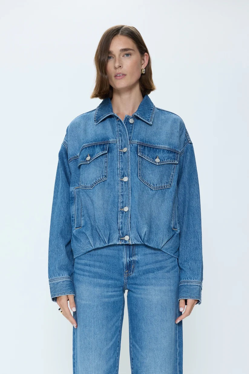 Person wearing a blue denim jacket and jeans on a white background