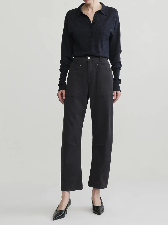 A model wearing a dark navy long-sleeve collared knit top and black wide-leg cropped trousers, paired with black pointed-toe heels, against a light gray studio background.