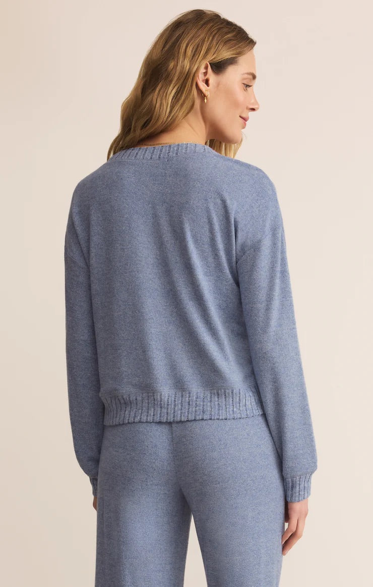 Woman wearing a blue sweater and pants on a beige background
