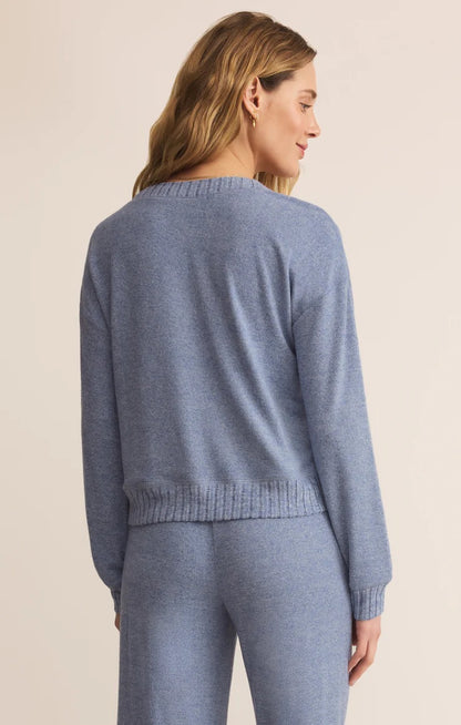Woman wearing a blue sweater and pants on a beige background