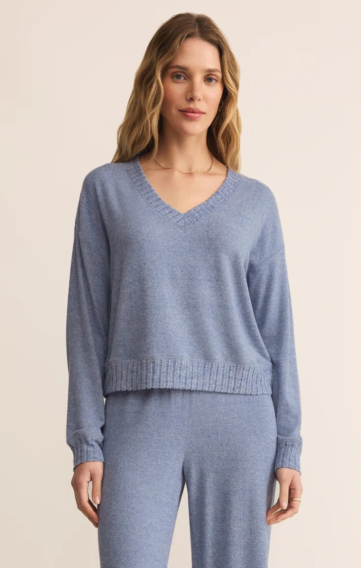 Woman wearing a blue sweater and pants on a beige background
