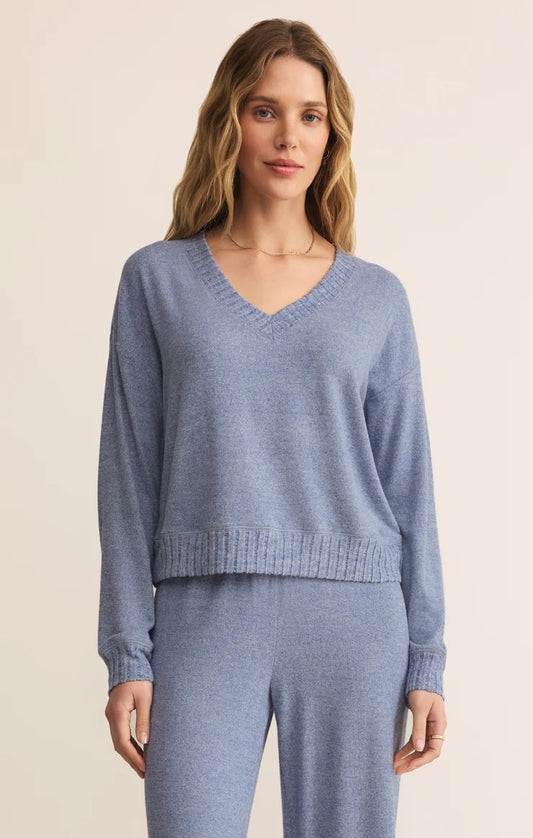 Woman wearing a blue sweater and pants on a beige background