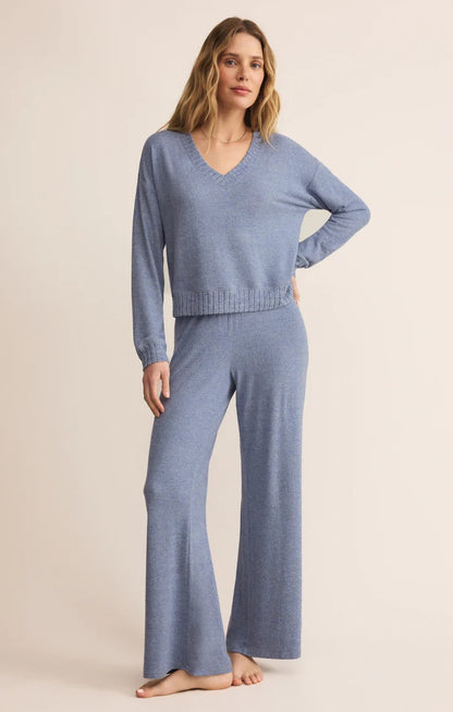 Woman wearing a blue knit sweater and pants on a beige background