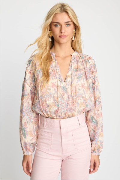 Woman wearing a floral blouse and pink pants on a white background