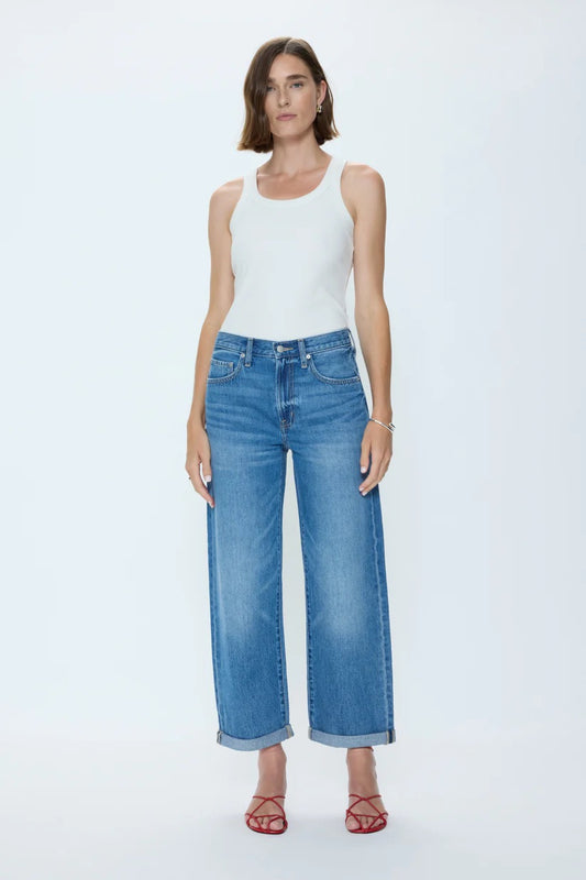 Woman wearing a white tank top and blue jeans on a white background