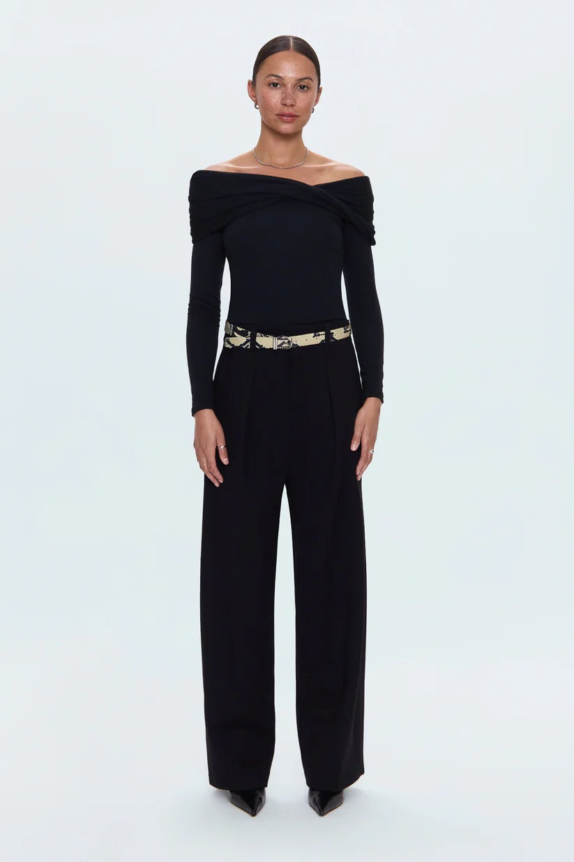 Woman wearing a black off-shoulder jumpsuit with a belt on a white background