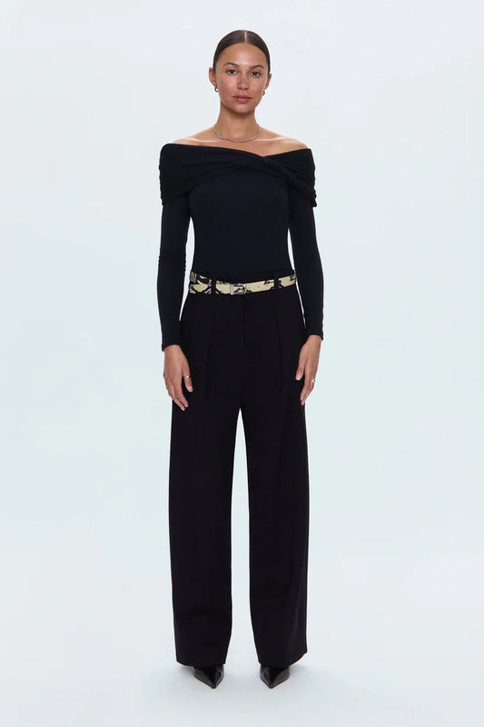 Woman wearing a black off-shoulder jumpsuit with a belt on a white background