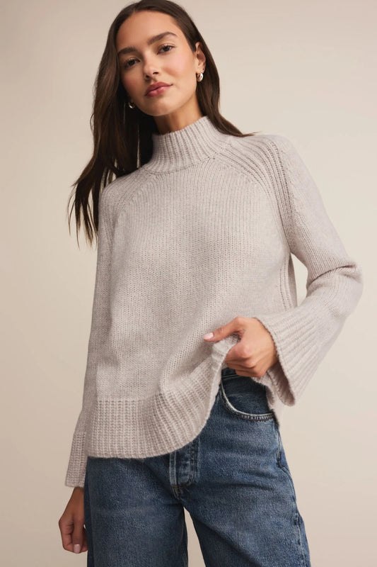 Woman wearing a light gray knit sweater against a neutral background