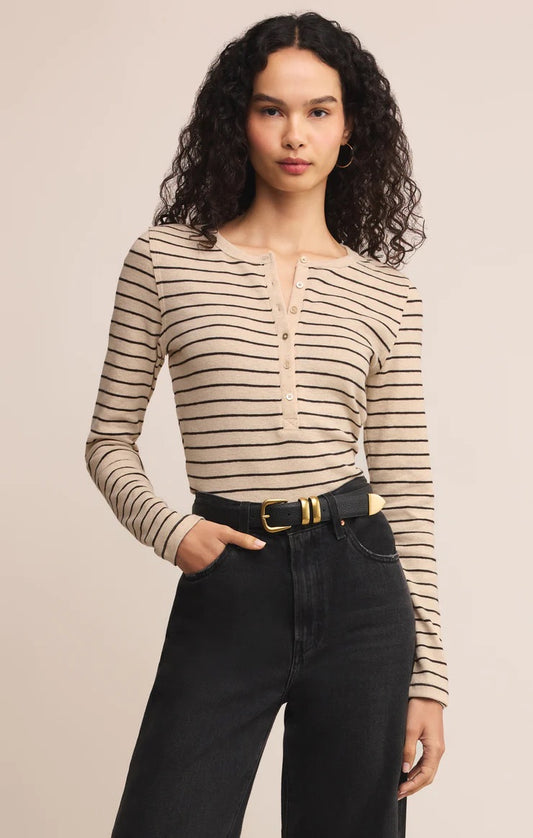 women in stripped henley shirt posed in front of a beige background