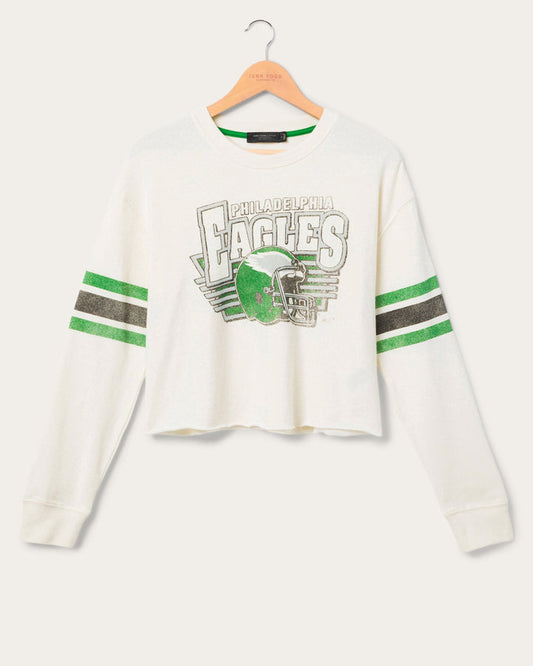 White cropped longsleeve eagles tshirt feature the football team Eagles logo with stripes on the sleeves on a hanger in front of a white background
