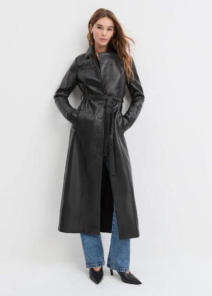 Woman wearing a black leather trench coat on a white background