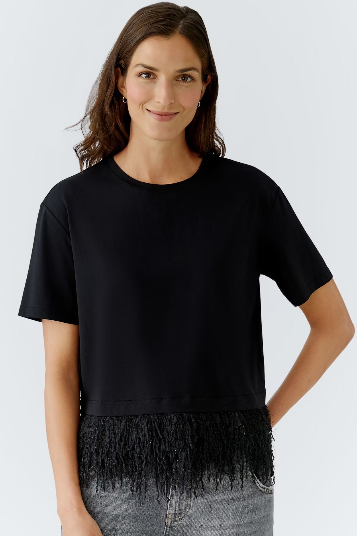 Woman wearing a black t-shirt with fringe details on a white background