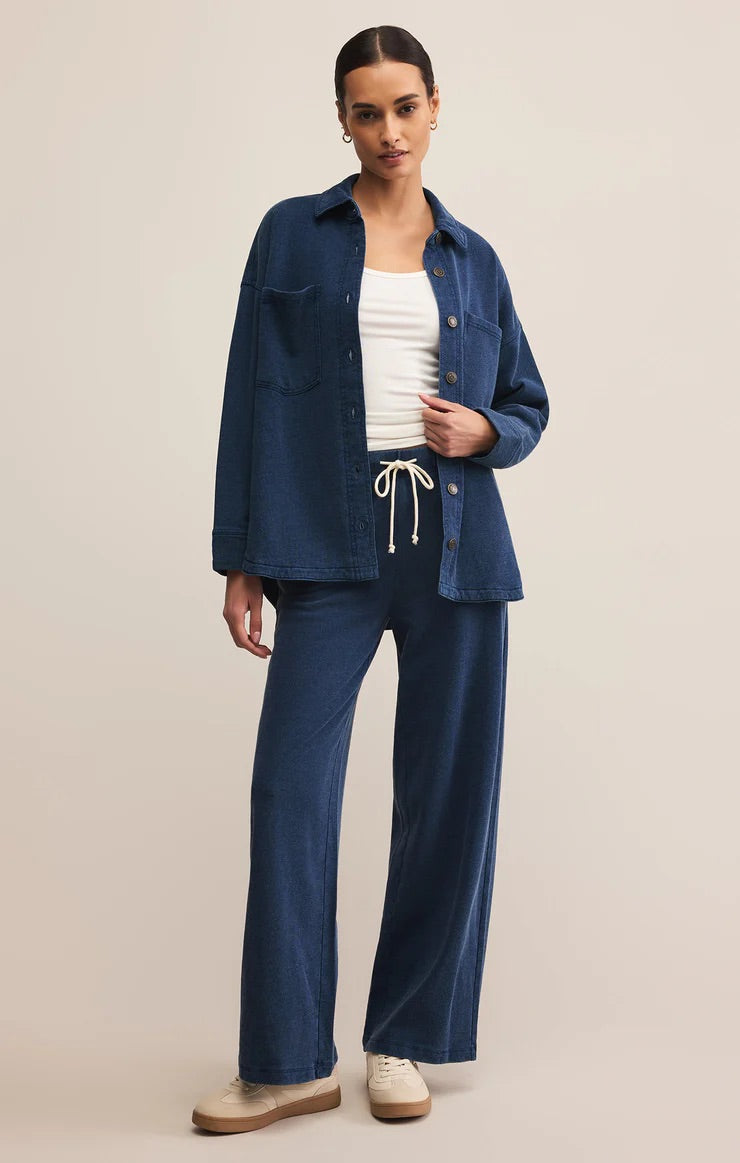 Woman wearing a blue denim jacket and pants on a beige background