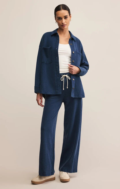 Woman wearing a blue denim jacket and pants on a beige background